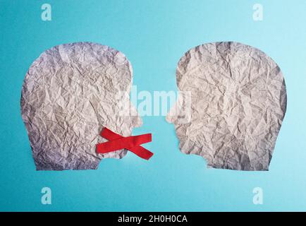 Due facce di silhouette si guardano l'un l'altro, una ha una croce rossa sopra la sua bocca, censura libera parola Foto Stock