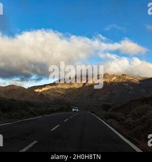 Auto che guida sulla strada TF-24 attraverso il paesaggio vulcanico, vicino al vulcano Pico del Teide, luce notturna, Parco Nazionale del Teide, Tenerife, Spagna Foto Stock