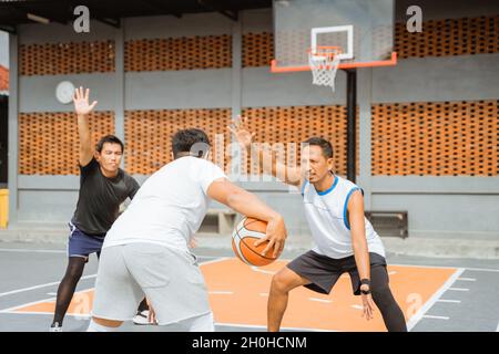 il giocatore tiene la palla sparando tre punti nel cerchio Foto Stock