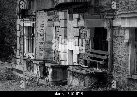 SADON, RUSSIA - 07 25 2021: Vecchio edificio abbandonato in rovinato da fango piccola città alta in montagna con vecchio segno sovietico Grocery Store 2 in russo Foto Stock
