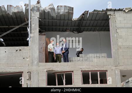 (211013) -- CITTÀ DI GAZA, 13 ottobre 2021 (Xinhua) -- Philippe Lazzarini (R), commissario generale dell'Agenzia delle Nazioni Unite per il soccorso e l'occupazione dei profughi palestinesi nel Vicino Oriente (UNRWA), visita la casa della famiglia Salmiya, danneggiata dagli attacchi aerei israeliani durante l'ultima ondata di tensione in maggio, Al campo profughi di al-Shati a Gaza, il 12 ottobre 2021. Lazzarini ha raccontato una conferenza stampa prima che l'agenzia iniziasse a ricostruire una casa distrutta in un campo profughi nella città occidentale di Gaza come l'inizio del processo di ricostruzione delle case dei rifugiati. (Foto di Rizek Abdeljawad/Xinhua) Foto Stock