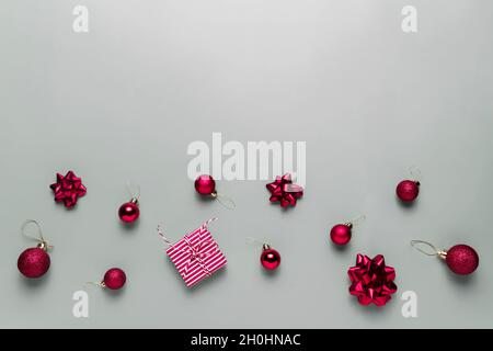 Sfondo grigio con regalo scatola rosa Natale presente, palline rosse di Natale o giochi sfera, archi a nastro per abete, altre decorazioni. Natale Foto Stock