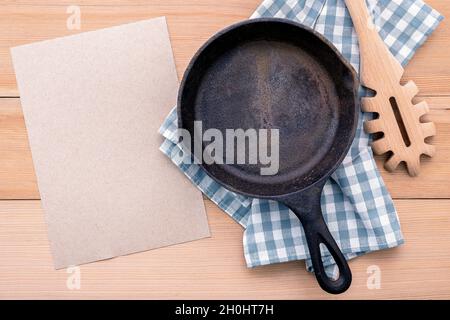 Cibi italiani del concetto e del design del menu . Svuotare padella in ghisa e pasta siviera su sfondo di legno. Foto Stock