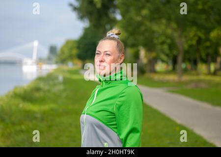 Fit donna sana godendo di una corsa lungo una riva del fiume pausa per ammirare la vista con un sile in un ritratto del corpo in primo piano in uno stile di vita attivo co Foto Stock