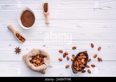 Cacao in polvere e chicchi di cacao su sfondo di legno. Cioccolato fondente pezzi frantumato e erbe aromatiche . Foto Stock