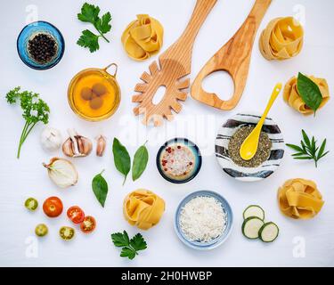 Cucina italiana e design del menu. Fettuccine secche fatte in casa con spatola di legno e ingredienti basilico dolce, pomodoro, aglio, prezzemolo, foglie di alloro Foto Stock