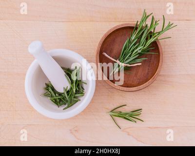 Rosmarino fresco medicina di erbe in un mortaio e ciotola di legno sul tavolo di legno Foto Stock