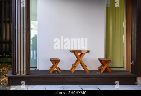 Tavoli e sedie in legno posti di fronte alla casa moderna. Foto Stock