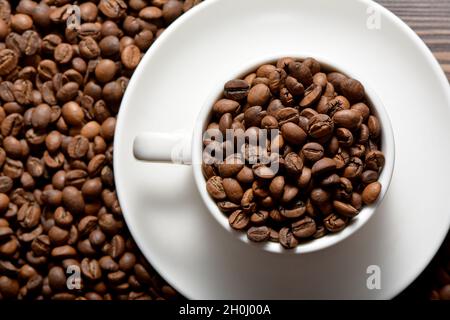 Tazza di caffè bianca ripiena di chicchi di caffè Foto Stock