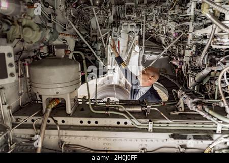 Pilota che guarda le condizioni tecniche dell'aeromobile nell'hangar Foto Stock