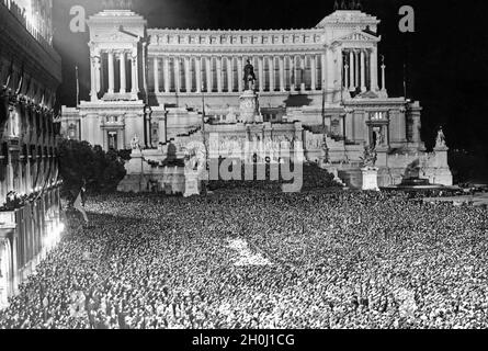 Decine di migliaia di persone si sono riunite in Piazza Venezia la sera del 7 maggio 1938 per celebrare Adolf Hitler e Benito Mussolini che si ergono di fronte al Palazzo Venezia (a destra, non raffigurato) con la frenetica Grazie. Sia il Vittoriano (centro della foto) che il Palazzo delle Assicurazioni generali (a sinistra) sono illuminati. Hitler si era recato a Roma per una visita di stato da parte del suo alleato Mussolini. [traduzione automatizzata] Foto Stock