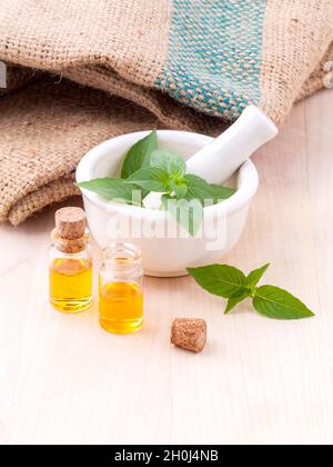 Medicina alternativa basilico limone olio naturale terme ingredienti per aroma aromaterapia con mortaio su sfondo di legno. Foto Stock