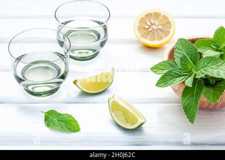 Ingredienti per rendere i mojito con foglie di menta, calce,limone e vodka su sfondo rustico. Foto Stock