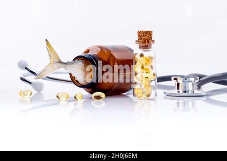 Olio di fegato di pesce di capsule in bottiglia con uno stetoscopio isolare su sfondo bianco. Foto Stock