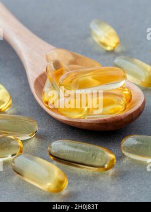 Close up capsule olio di pesce in cucchiaio di legno .Il supplemento alta vitamina E omega 3, DHA e EPA Foto Stock