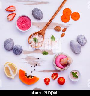 In casa di cura di pelle e scrub corpo rosso con ingredienti naturali fragola , Pomodoro ,Sale Himalayano, mature papaia, carota e spa setup di pietra su bianco Foto Stock