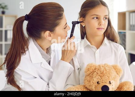 Otolaryngologist che esamina l'orecchio del bambino con otoscopio durante il controllo al suo ufficio Foto Stock