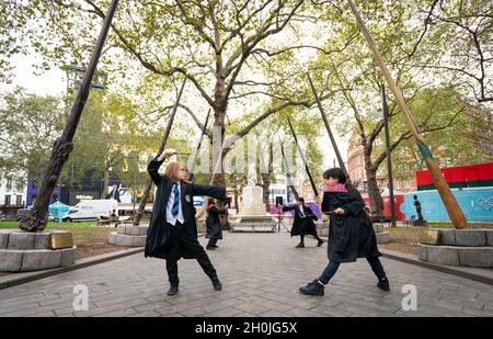 Gli allievi della scuola Park View di Haringey, Londra, prendono parte alla lezione di bacchetta magica di Harry Potter, all'inaugurazione di nove sabbie alte 15ft in Leicester Square, Londra, per celebrare il ventesimo anniversario del film di Harry Potter e della pietra del filosofo. Data foto: Mercoledì 13 ottobre 2021. Foto Stock