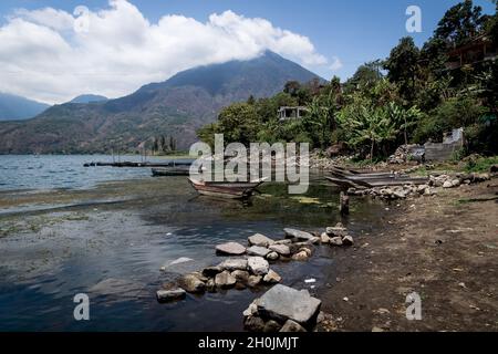 Baia sul lago Atitlan con piccole barche da pesca in legno con vista sulla foresta e paesaggio vulcanico di montagna, Santiago Atitlan, Guatemala Foto Stock