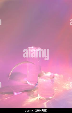 due podi in vetro trasparente su sfondo rosa pastello Foto Stock