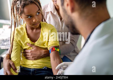 Il pediatra prende il sangue da un paziente bambino. Concetto di coronavirus di test degli anticorpi sanitari Foto Stock