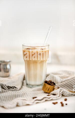Caffè latte ghiacciato in un bicchiere alto su sfondo bianco Foto Stock