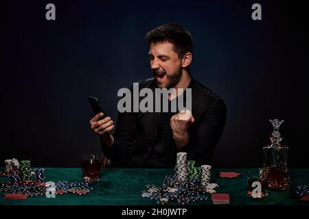 Uomo giocatore di casinò bearded che gioca a poker su tavolo verde Foto Stock