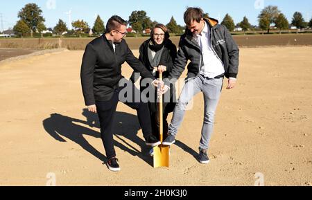 Roggentin, Germania. 13 ottobre 2021. Christian Baudisch (l-r), Managing Director, Raijana Schiemann, biologo e Managing Director, e Nico Funck, Future Production Manager, rompono simbolicamente il terreno con una lancia dorata per un impianto di produzione di farine di insetti della giovane azienda di start-up di Rostock Inova Protein. Nell'area di produzione di quasi 800 metri quadrati, in futuro saranno prodotte 1.5 tonnellate di farina di insetti al mese a partire da polli destinati ai prodotti alimentari. A maggio, il verme giallo (Tenebrio molitor) è stato il primo insetto approvato dall'UE come nuovo prodotto alimentare. Credit:/dpa/Alamy Live News Foto Stock