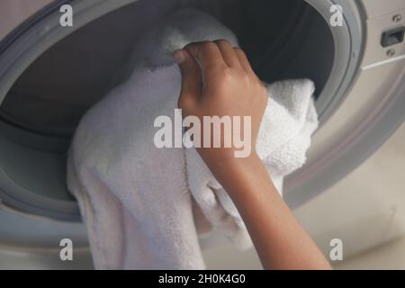 uomo che mette la camicia nella lavatrice. Foto Stock