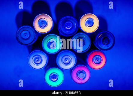 13 ottobre 2021, Meclemburgo-Pomerania occidentale, Neubrandenburg: Bottiglie spray vuote con colori al neon sono sotto luce UV nel futuro campo da mini-golf al neon in un ex locale industriale. Da oltre un anno, tre artisti lavorano in totale ai nove mondi tematici. I futuri visitatori della struttura per il tempo libero possono vedere solo le immagini composte da un massimo di otto strati di vernice con motivi del mondo sottomarino, la giungla o templi storici sotto la luce nera nelle camere oscurate. Foto: Jens Büttner/dpa-Zentralbild/dpa Foto Stock