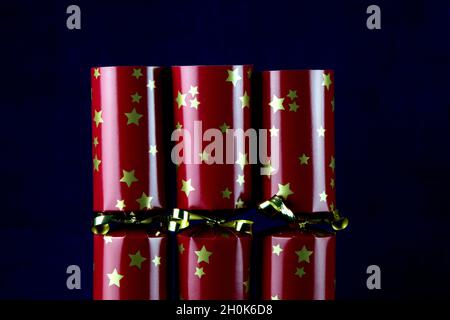 Vista verticale di tre cracker rossi di natale isolati su uno sfondo blu Foto Stock