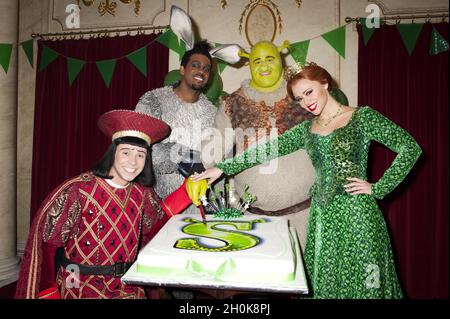 Neil McDermott che suona Lord Farquaad, Richard Blackwood che suona l'asino, Dean Chisnell che suona Shrek e Kimberley Walsh che suona la principessa Fiona ha tagliato la torta a Shrek il Fete della famiglia di 1 anno di anniversario musicale al Drury Lane Theatre di Londra Foto Stock