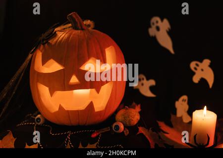 Decorazione di Halloween sul tavolo. Zucca di Halloween. Prelibatezze tradizionali. Primo piano in Pumpkin con grande paura. Zucca incandescente Foto Stock