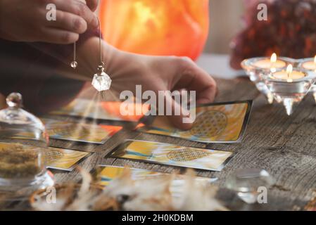 Indovino tenendo un pendolo su carte dei tarocchi Foto Stock