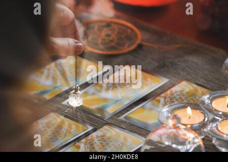 Indovino tenendo un pendolo su carte dei tarocchi Foto Stock