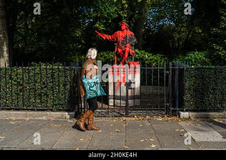 BELGRAVE SQUARE LONDRA, REGNO UNITO. 13 Ott 2021. Un osservatore guarda la statua di Cristoforo Colombo nella Belgrave Square di Londra, che è stata ricoperta di vernice rossa dai membri della Rebellion di estinzione per i suoi legami con il razzismo e il colonialismo nell'anniversario del giorno in cui è arrivato in America. La statua dell'esploratore italiano Cristoforo Colombo è stata progettata dallo scultore Tomas Banuelos per commemorare il 500° anniversario della spedizione di Colombo nel nuovo mondo ed è un dono del popolo spagnolo..Credit: amer Ghazzal/Alamy Live News Foto Stock