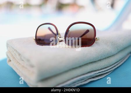 Occhiali da sole adagiati su asciugamani di cotone marrone sul lettino Foto Stock