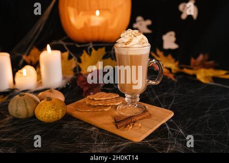 Latte di Halloween. Caffè latte piccante in decorazioni di Halloween. Zucca, latte, Halloween, contenuti commerciali. Tazza di caffè sul tavolo di Halloween Foto Stock