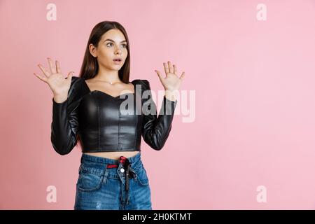 Ritratto corto di giovane donna emotiva mettendo le mani su isolato su sfondo rosa. Espressione scioccata Foto Stock