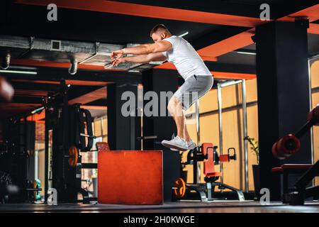 Giovane atletica allenarsi in palestra saltando a cubo. Vista laterale. Il concetto di fitness e di allenamento. Foto Stock
