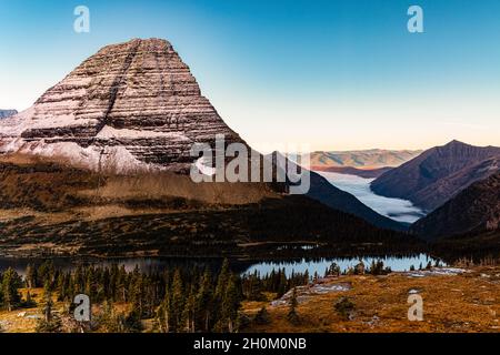 Bear Hat Mountain con copertura innevata, lago nascosto e nebbia protetta McDonald Valley sotto, Glacier National Park, Montana, Stati Uniti Foto Stock