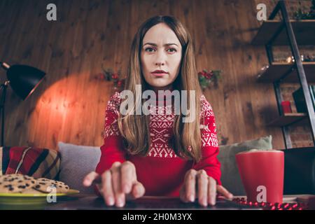 Foto di seria sicura signora matura indossare rosso pullover tipizzazione moderno dispositivo di natale casa al chiuso casa camera Foto Stock