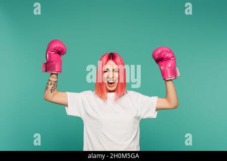 stupito giovane donna con capelli colorati rosa in guanti da boxe isolati su blu Foto Stock