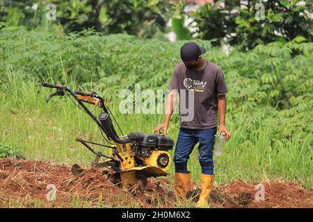 Bandung, Indonesia-29 settembre 2021: Gli agricoltori arano i campi utilizzando una macchina aratro Foto Stock