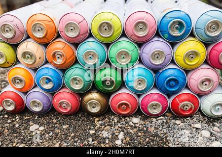 Le bombolette a spruzzo con coperchi tondi multicolore si trovano in file come modello Foto Stock