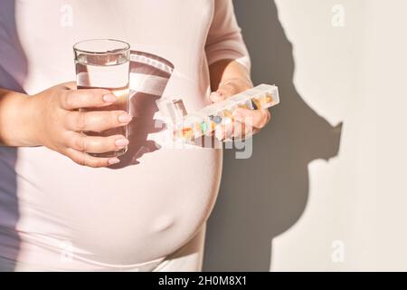 Donna incinta mangiare pillole di gravidanza. Integratori influenzali. Assunzione di farmaci allergici. Foto Stock