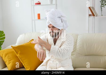 L'uomo bearded sfrega mano crema sulle sue mani. Spa, cura del corpo e della pelle per l'uomo concetto Foto Stock