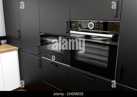 Cucina moderna con facciate nere, forno e microonde incorporati, pannelli in vinile sul pavimento. Foto Stock