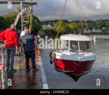 Arvor 230 Cabin Cruiser in fase di messa in moto dall'acqua con gru mobile e stroping di sollevamento del nastro Foto Stock