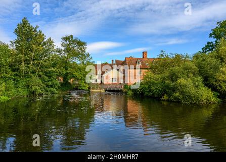 Gli edifici in mattoni rossi di Flatford Mill si affacciano dall'altra parte del fiume Stour nel 'Paese Constable', Suffolk, Inghilterra. Foto Stock